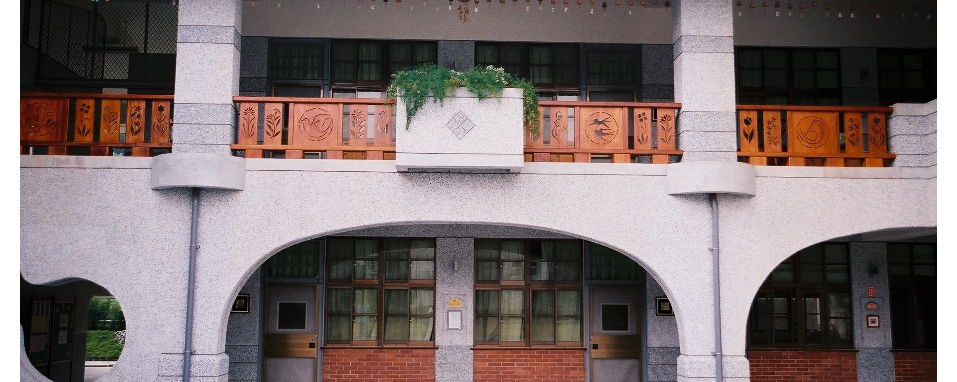 一樓走廊上的拱門造型及二樓有鏤空雕刻花鳥圖案的柚木欄杆